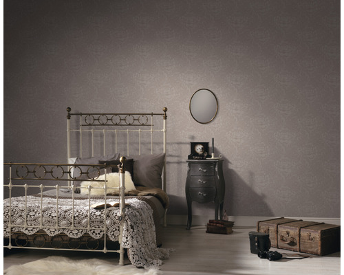 Chambre à coucher avec lit, table de chevet et papier peint à motifs pour une ambiance cosy.