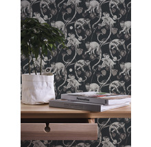 Dekorative Tapete mit Affen- und Pflanzenmotiven im Hintergrund, dazu eine Kommode mit Pflanze und Büchern.