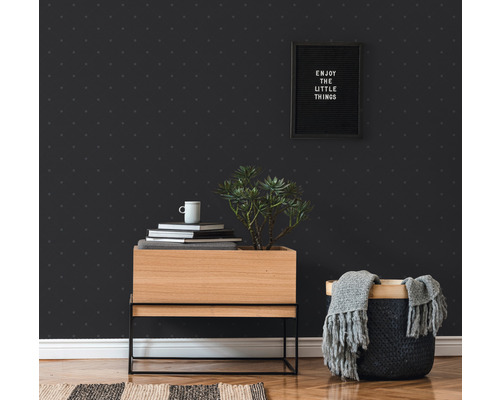 Raumansicht mit gemusterter Tapete, Holzkommode, Pflanze, Dekoration und Korb