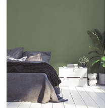 Schlafzimmer mit Bett, Nachttisch und grüner Wand