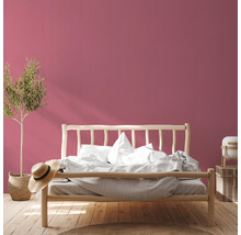 Schlafzimmer mit Holzbett, Pflanze und rosa Wand
