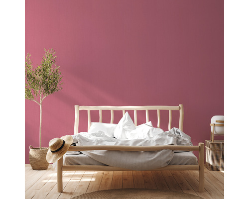 Schlafzimmer mit Holzbett, Pflanze und rosa Wand