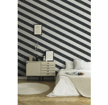 Schlafzimmer mit Bett, Kommode, Teppich und Wand mit gestreifter Tapete