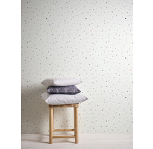 Papier peint à pois avec une pile de coussins sur un tabouret