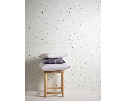 Papier peint à pois avec une pile de coussins sur un tabouret