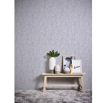 Arrangement décoratif avec vases, photos et banc en bois devant un mur avec papier peint texturé.