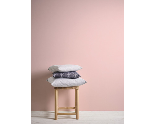 Coussins décoratifs sur un tabouret devant un mur