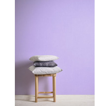 Coussins décoratifs empilés sur un tabouret devant un mur