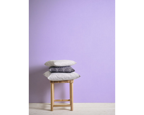 Coussins décoratifs empilés sur un tabouret devant un mur