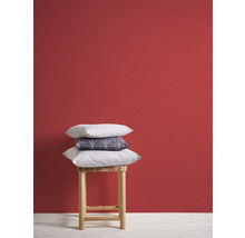 Coussins décoratifs sur un tabouret en bois devant un mur