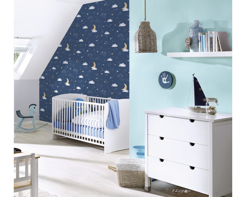 Chambre de bébé avec lit à barreaux, commode et papier peint bleu à motifs