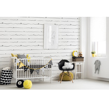 Chambre d''enfant décorée avec lit à barreaux, chaise et accessoires devant un papier peint à motifs.