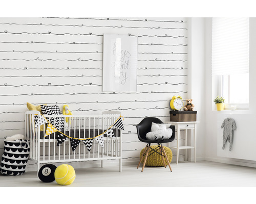 Chambre d''enfant décorée avec lit à barreaux, chaise et accessoires devant un papier peint à motifs.