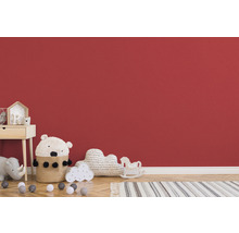 Chambre d''enfant avec table de chevet, jouets et tapis devant un mur rouge