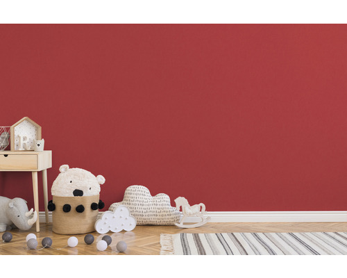 Chambre d''enfant avec table de chevet, jouets et tapis devant un mur rouge