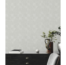 Wohnraum mit gemusterter Tapete, Kommode, Dekorationsgegenständen und Stuhl