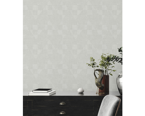 Wohnraum mit gemusterter Tapete, Kommode, Dekorationsgegenständen und Stuhl