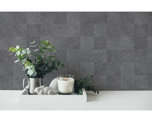 Dekoratives Arrangement mit einer Kerze, einer Pflanze und einer grauen Tapete mit Leinenstruktur