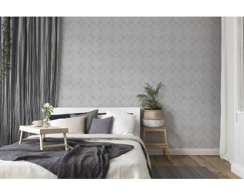 Chambre claire avec lit, table de chevet et papier peint géométrique