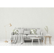 Wohnzimmer mit grauem Sofa, Kissen und Beistelltischen vor einer hellen Wand