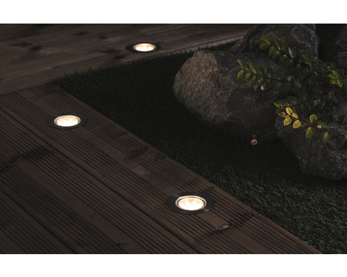 Scène avec éclairages extérieurs LED encastrés sur une terrasse en bois à côté de pierres et de plantes