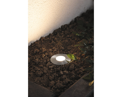 Bodeneinbaustrahler im Aussenbereich, eingebettet in Erde mit Pflanzen.