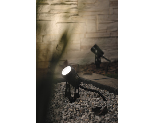 Zwei schwarze Gartenstrahler beleuchten einen Kiesweg