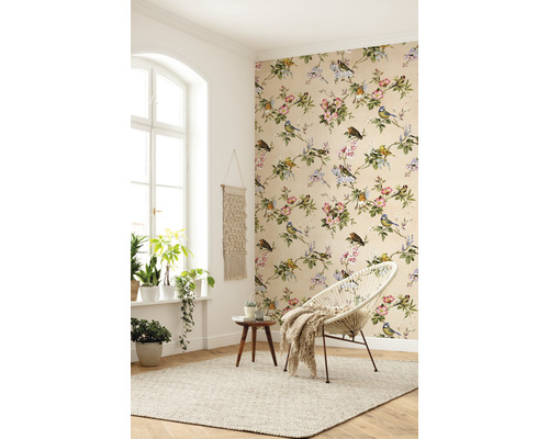 Heller Raum mit floraler Tapete, rundem Sessel und Zimmerpflanzen