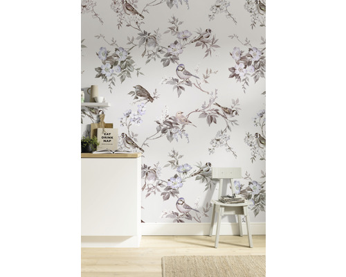 Raum mit Vogel- und Blumenmustertapete, einem weißen Schrank und einem Stuhl.