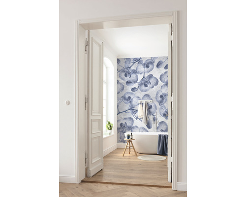 Helles Badezimmer mit Badewanne, Holzboden und Fototapete mit Orchideenmuster, aufgenommen durch eine geöffnete Tür.