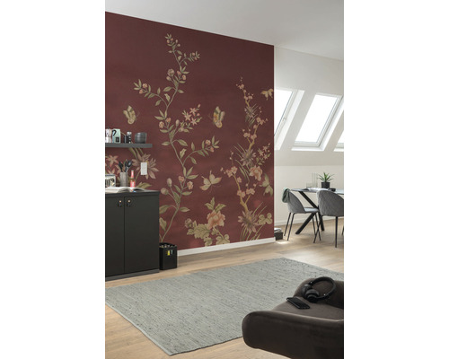 Wohnzimmer mit floral gemusterter Tapete in Rotbraun, Esstisch, Stühlen und grauem Teppich.