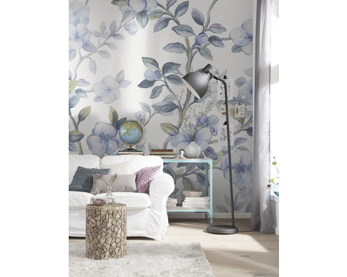 Dekorierter Wohnraum mit Sofa, Beistelltisch und Stehlampe vor einer floralen Tapete