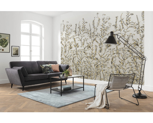 Wohnzimmer mit Sofa, Teppich, Stehlampe, Stuhl und gemusterter Tapete mit Pflanzenmotiven