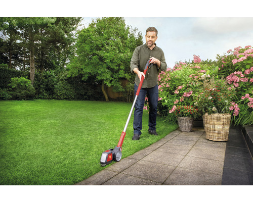 Mann schneidet Rasenkanten mit Rasenkantenschneider im Garten