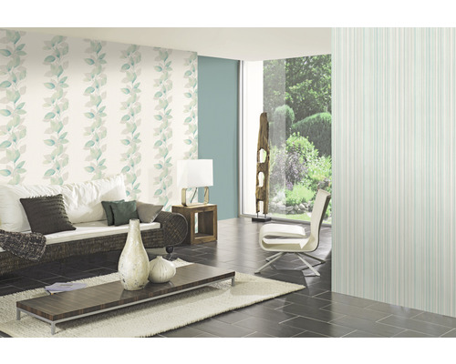 Salon avec papier peint floral, canapé, table et fauteuil.