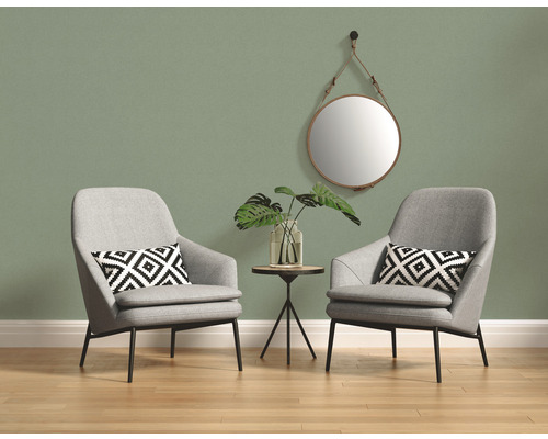 Zwei graue Sessel mit Kissen, Tisch, Spiegel und Pflanze vor einer Wand