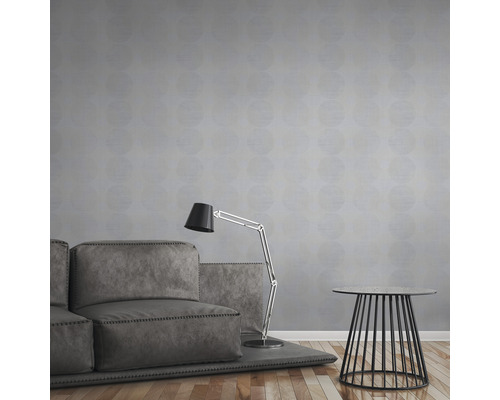 Un salon avec un canapé, un lampadaire et une table d''appoint devant un mur avec du papier peint à motifs