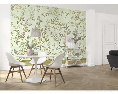 Ein Esszimmer mit einer Wandtapete mit Vogel- und Blumenmuster, einem Esstisch und Stühlen.