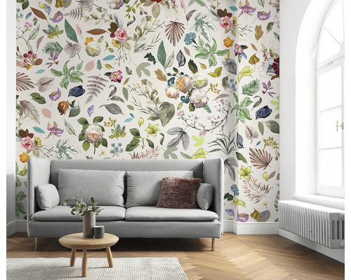 Wohnzimmer mit Sofa und floraler Tapete mit Blättern und Blüten.