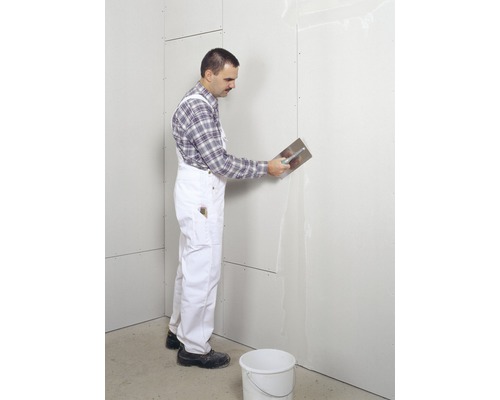 Handwerker verspachtelt Gipskartonwand mit einem Spachtel
