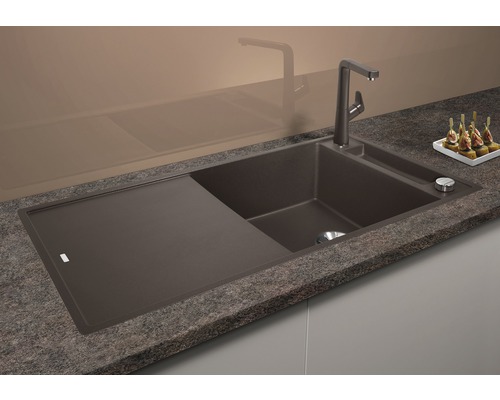 Évier en matériau composite avec égouttoir et robinet sur un plan de cuisine.