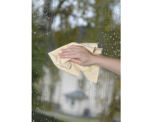 Une main essuie une surface vitrée avec un chiffon