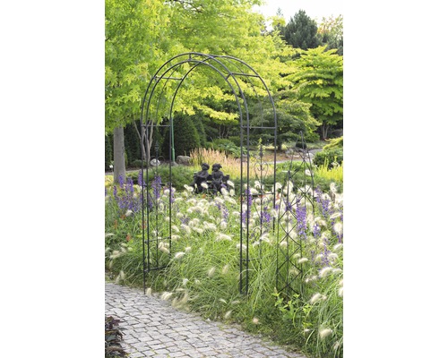 Gartenszene mit Rosenbogen, Ziergräsern und Pflasterweg