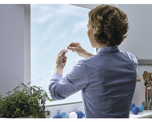 Une femme fixe une décoration de fenêtre à la fenêtre