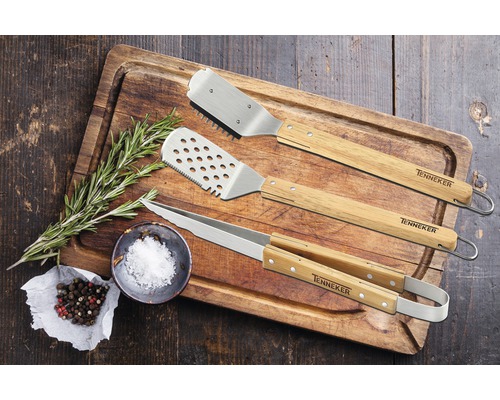 Barbecue-Besteckset mit Zange, Pfannenwender und Grillgabel auf einem Holzbrett