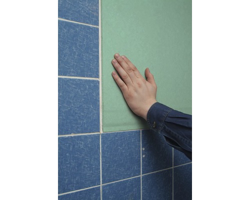 Main sur une plaque de construction à côté de carreaux bleus