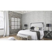 Chambre claire avec lit, tables de chevet, banc et papier peint mural en briques