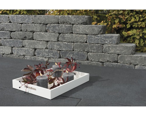 Pierres de mur empilées avec des bougies sur un plateau dans le jardin.