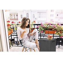 Frau auf Balkon mit Aufbewahrungsbox, Tasse und Tablet