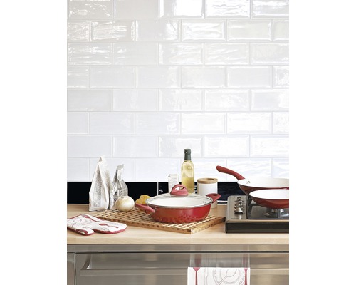 Küchenszene mit Kochgeschirr, Zutaten und weißen Fliesen